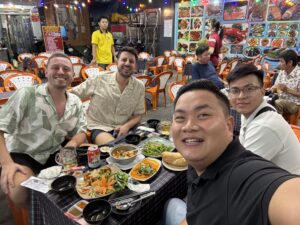 Travelers enjoying Vietnamese street food at Saigon night market – Taste & Tales of Vietnam tour experience.
