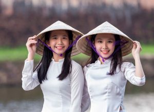 Vietnamese woman wearing a conical hat while rowing a boat in the Mekong Delta