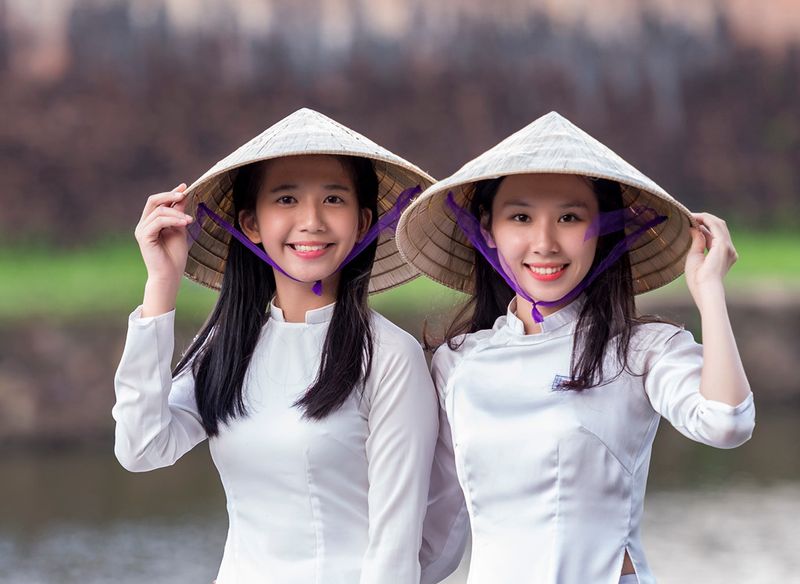 Vietnamese woman wearing a conical hat while rowing a boat in the Mekong Delta