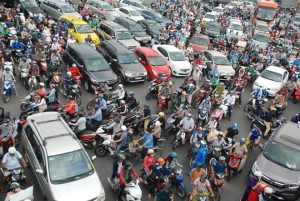 Tourist crossing a busy street full of motorbikes in Ho Chi Minh City, Vietnam