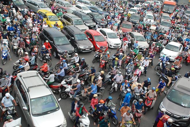 Tourist crossing a busy street full of motorbikes in Ho Chi Minh City, Vietnam